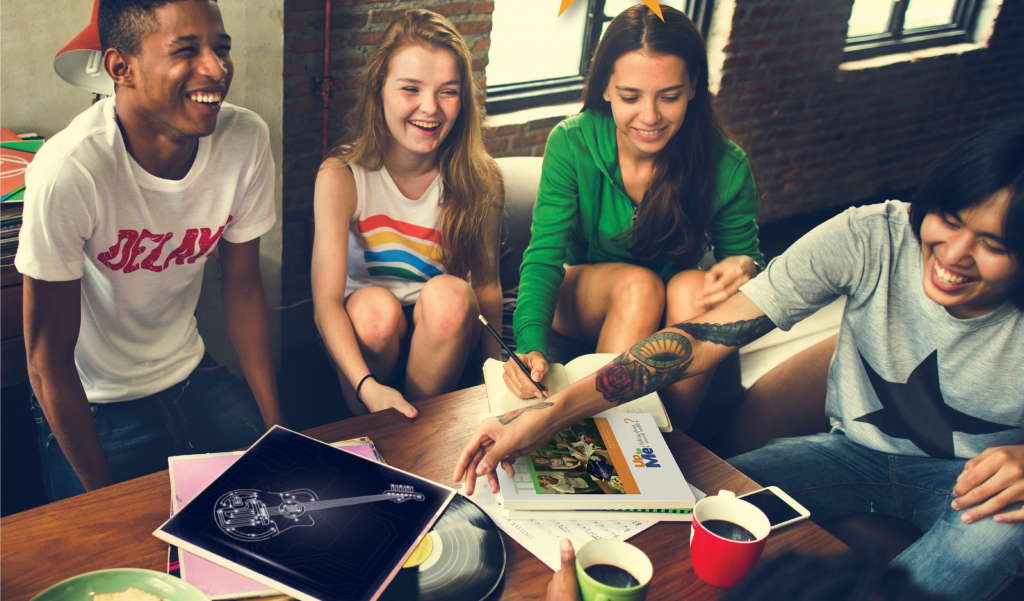 A group of 4 teenagers in a casual setting in a conversation, laughing and smiling.