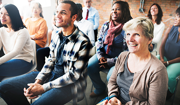 A group of people sitting and attentively listening in an informal gathering.